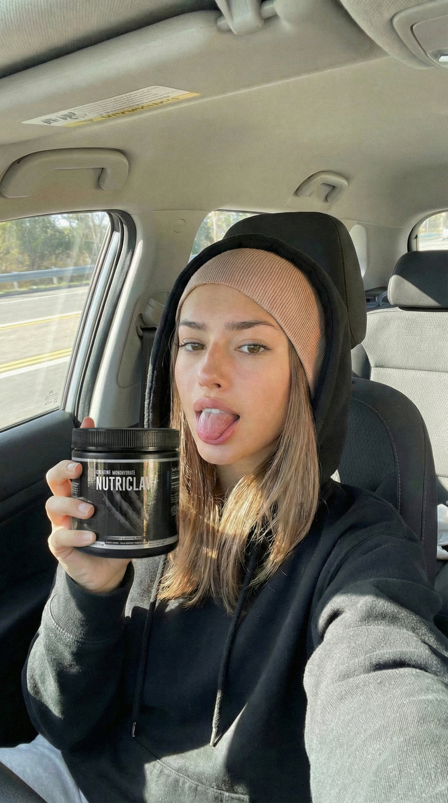 Woman in a car holding a NutriClaw supplement container